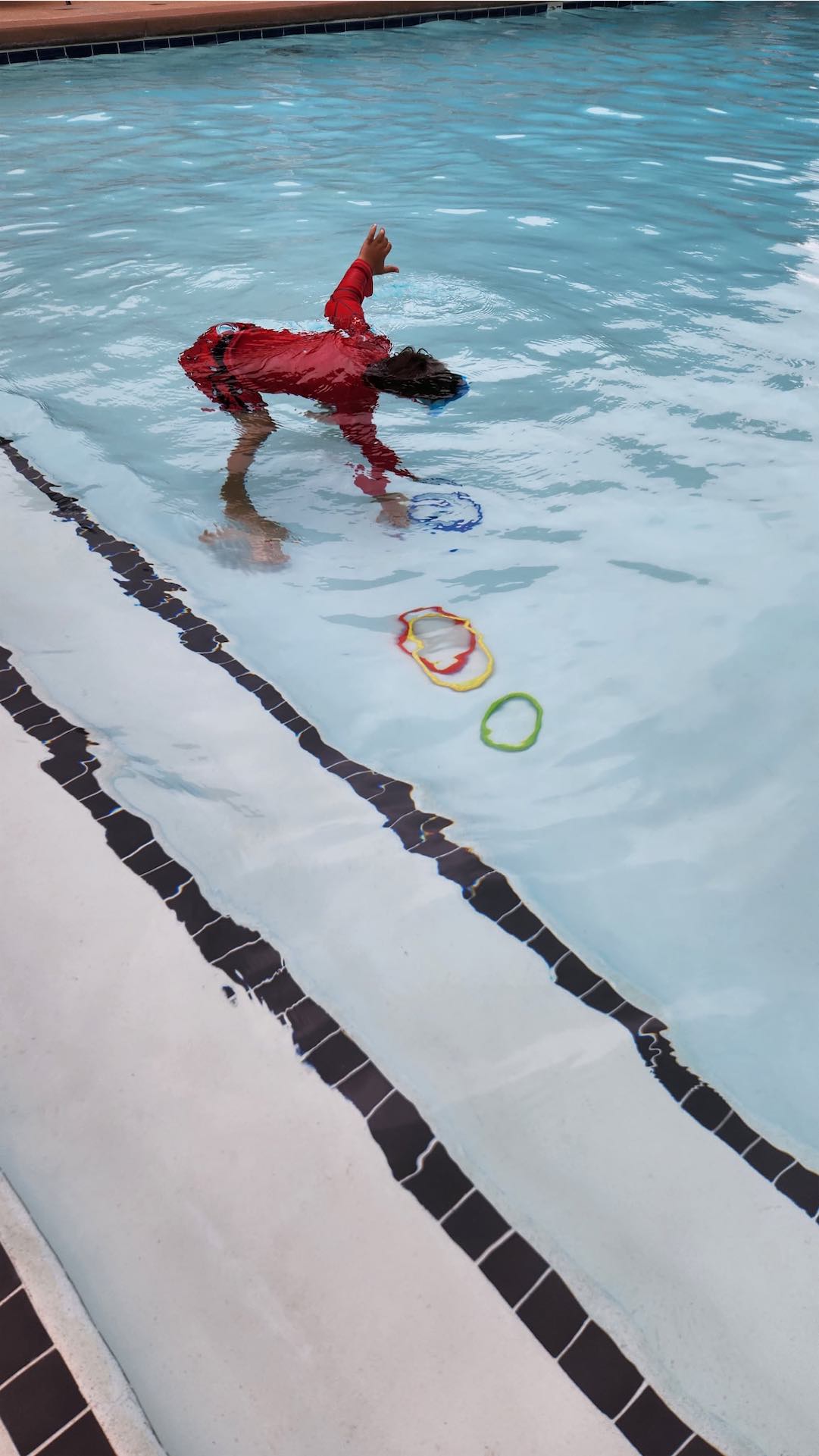 Kids lined up at the pool edge ready to practice jumping in safely