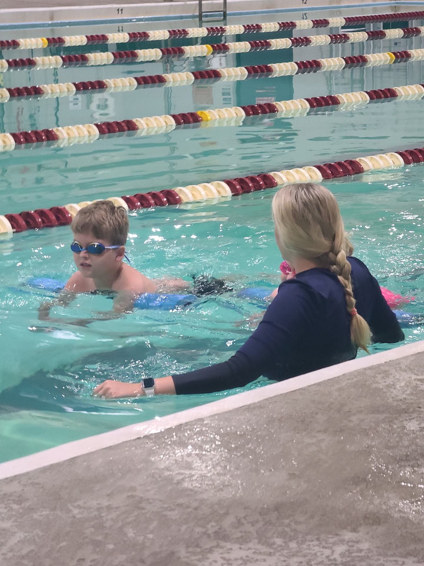 Young swimmer receiving stroke correction from a Like a Fish coach